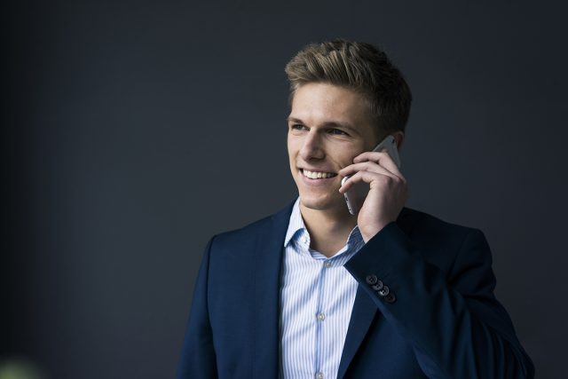 Sales call preparation – Portrait of smiling young businessman on cell phone