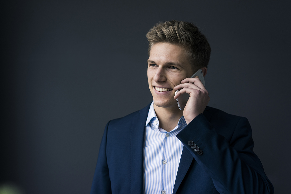 Sales call preparation – Portrait of smiling young businessman on cell phone